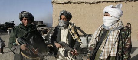 In this photo taken Monday, Oct.19, 2009, Taliban militants stand beside the burnt trucks, background left, on main Ghazni- Kandahar highway in Ghazni, west of Kabul, Afghanistan. Taliban militants set fire to 15 trucks carrying supplies to a military base in eastern Ghazni province, according to local official Sahib Khan. Afghan security guards killed two militants during the fighting. (AP Photo/Rahmatullah Naikzad )