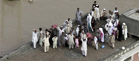 Stranded Pakistani villagers wait for rescue helicopters on their house in Nowshera, Pakistan on Friday, July 30, 2010. Boats and helicopters struggled to reach hundreds of thousands of villagers cut off by floods in northwest Pakistan on Friday as the government said it was the deadliest such disaster to hit the region since 1929. (AP Photo/Mohammad Sajjad)