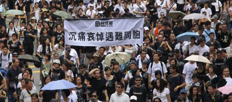 Ten of thousands of Hong Kongers march through a downtown street in Hong Kong, on Sunday, Aug, 29, 2010 in honor of victims of Manila bus hijacking, in lingering outrage over the bloodshed that devastated this southern Chinese territory that rarely sees violent crime. The Chinese words on banner reads " Deeply in sorrow to mourn the victims." (AP Photo/Vincent Yu)