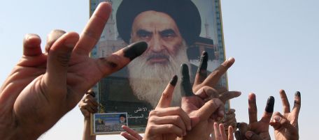 Iraqi Shiites flash victory signs, showing off their ink marked fingers, after voting in Iraq's constitution referendum, in Baghdad, Iraq, Saturday Oct. 15 2005.Iraqis vote Saturday to give a "yes" or "no" to a constitution that would define democracy in Iraq, a country once ruled by Saddam Hussein and now sharply divided among its Shiite, Sunni and Kurdish communities.The poster shows prominent Shiite cleric Grand Ayatollah Ali al-Sistani. (AP Photo/Karim Kadim)