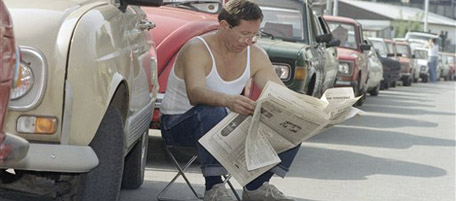 A man reads a newspaper as he waits in line for gasoline on Monday, Sept. 14, 1992 in Belgrade, Yugoslavia in hope that gasoline will be delivered to this station. Despite fuel rationing of 5.2 gallons per month, most of the gasoline stations in Yugoslav capital are dry. (AP Photo)
