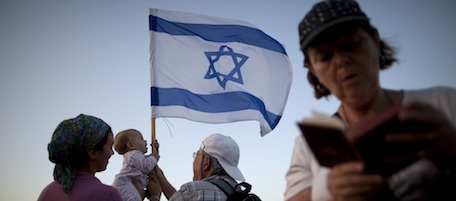 Jewish settlers hold an Israeli flag during a protest march near the Jewish settlement of Yitzhar, near Nablus, Monday, Oct. 4, 2010. Several dozens Jewish settlers from Yitzhar and their supporters marched Monday in protest of an Israeli court decision that they said ordered the demolition of a synagogue in a Jewish settlement, while ignoring a mosque which they say was built illegally in the Palestinian village of Burin. Scores of Palestinians protested near the settlers march, but both demonstrations ended without any violent incidents. (AP Photo/Oded Balilty)