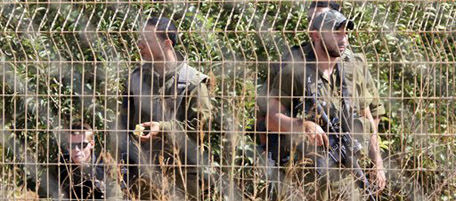 Israeli soldiers eat apples in the Israeli town of Metulla, seen from the southern border village of Kfar Kila, Lebanon, Thursday, Oct. 14, 2010. Iranian President Mahmoud Ahmadinejad came to the doorstep of his archenemy Israel on Thursday, telling tens of thousands of Hezbollah supporters in a Lebanese border town he was proud of their struggle as Israeli helicopters buzzed the skies along the tense frontier. (AP Photo/Mohammed Zaatari)