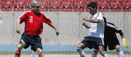 Chile's President Sebastian Pinera, left, controls the ball next to rescued miner Jimmy Sanchez, right, during a friendly soccer game at the National Stadium in Santiago, Chile, Monday, Oct. 25, 2010. (AP Photo/Roberto Candia)