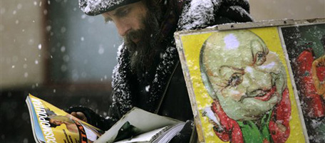 A street artist reads a magazine during a snowfall in downtown Moscow, Monday, Jan. 30, 2006. Snow fell Monday across Moscow, while temperatures reached -1 Celsius (30 Fahrenheit). (AP Photo/Ivan Sekretarev)