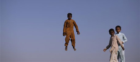 Pakistani flood displaced boys look on while another jumps on a trampoline next to their camp in Basira village, Punjab Province, Pakistan, Wednesday, Nov. 3, 2010. (AP Photo/Muhammed Muheisen)