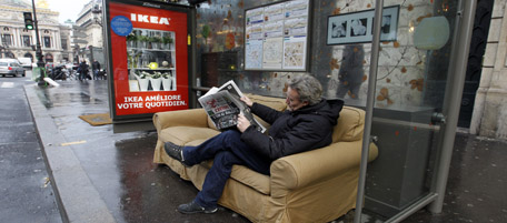 A man poses at a bus station in a couch that was placed there by Swedish home-furnishing giant Ikea to promote its products, on December 20, 2010 in Paris. AFP PHOTO FRANCOIS GUILLOT (Photo credit should read FRANCOIS GUILLOT/AFP/Getty Images)