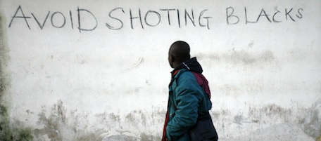 An immigrant worker walks by a wall reading "Avoid shooting Blacks" on January 9, 2010 after clashes with residents took place overninght in the southern Italian town. Authorities and reports said that residents beat with iron bars, shot at and ran over immigrants, wounding nine -- two seriously -- in a second night of racially charged violence. AFP PHOTO / Carlo Hermann (Photo credit should read CARLO HERMANN/AFP/Getty Images)