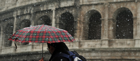 People walk past Rome's colosseum as snow falls on December 17, 2010. Snow fell in Pisa and Florence as well as Rome and the island of Capri. AFP PHOTO / FABIO MUZZIs (Photo credit should read ALBERTO PIZZOLI/AFP/Getty Images)