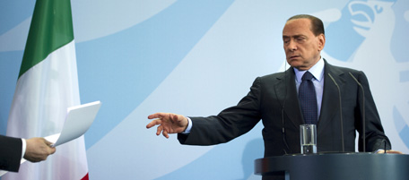 Italy's Prime Minister Silvio Berlusconi reaches out for documents during a press conference with Germany's Chancellor Angela Merkel (unseen) at the Chancellory in Berlin on January 12, 2011 after German-Italian government talks. Merkel said that she was pleased by the results of Portugal's closely watched bond auction, praising Lisbon for its "very impressive" austerity measures. AFP PHOTO / JOHANNES EISELE (Photo credit should read JOHANNES EISELE/AFP/Getty Images)