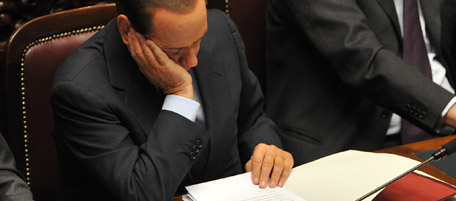 Italian Prime Minister Silvio Berlusconi (C) reads documents as he is flanked by foreign minister Franco Frattini (L) and economy minister Giulio Tremonti prior a confidence vote at the Chamber of Deputies, the Italian lower house, on December 14, 2010 in Rome. Italy held its breath as lawmakers staged a knife-edge confidence vote on Prime Minister Silvio Berlusconi's government that could bring down the flamboyant Italian leader. AFP PHOTO / ANDREAS SOLARO (Photo credit should read ANDREAS SOLARO/AFP/Getty Images)