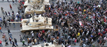 Egyptian demonstrators demanding the ouster of President Hosni Mubarak carry the body of a dead comrade wrapped in the Egyptian flag past Egyptian army tanks during his funeral in Cairo on January 29, 2011. AFP PHOTO/KHALED DESOUKI (Photo credit should read KHALED DESOUKI/AFP/Getty Images)