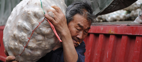 A Chinese worker unloads bags of garlic at a market in Hefei, central China's Anhui province on May 19, 2010. China said that consumer prices and bank lending accelerated in April, fuelling fears the economy may overheat and building pressure on Beijing to hike interest rates and let its currency rise. CHINA OUT AFP PHOTO (Photo credit should read AFP/AFP/Getty Images)