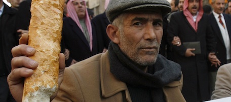 A Jordanian man brandishes a loaf of bread with a sign reading "No for price rises", during a protest against rising prices, in Amman, Jordan, Friday, Jan. 14, 2011. More than 5,000 Jordanians took to the streets Friday to protest against the rising prices of food and fuel. (AP Photo/Nader Daoud)