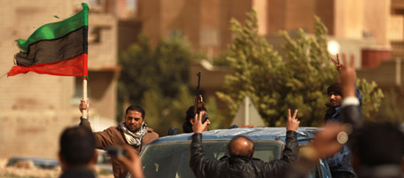 A member of Libya's Internal Security Forces (ISF) waves his old national flag ISF members parade in the eastern city of Tobruk on February 24, 2011. Residents of Libya's dissident-held east, frenzied by a deadly crackdown by Moamer Kadhafi's crumbling regime, vowed to march on the capital Tripoli as a string of towns famous as World War II battlegrounds fell under their control. AFP PHOTO/STR (Photo credit should read -/AFP/Getty Images)