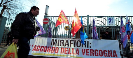 An employee walks past a banner which translates as " the shame agreement" at the Mirafiori Fiat plant in Turin on January 13, 2011. The 5,500 workers at Turin's Mirafiori plant will be employed under a joint Fiat-Chrysler venture and as such will no longer have the standard national industry contract, judged to be too restrictive by Fiat. A referendum on the deal, which has sparked a heated debate in Italy, is due to take place at the plant on January 13-14, 2011. AFP PHOTO / GIUSEPPE CACACE (Photo credit should read GIUSEPPE CACACE/AFP/Getty Images)