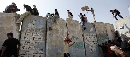 Iraqi anti-government protesters climb and push concrete blast walls leading to the heavily guarded Green Zone during a demonstration in Baghdad, Iraq, Friday, Feb. 25, 2011. Thousands marched on government buildings and clashed with security forces in cities across Iraq on Friday, in the largest and most violent anti-government protests here since political unrest began spreading in the Arab world several weeks ago. (AP Photo/Hadi Mizban)