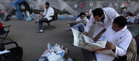 Egyptian anti-government doctors read the papers at a makeshift clinic in Cairo's Tahrir square on February 09, 2011, on the 16th day of protests against the regime of President Hosni Mubarak. AFP PHOTO/PATRICK BAZ (Photo credit should read PATRICK BAZ/AFP/Getty Images)