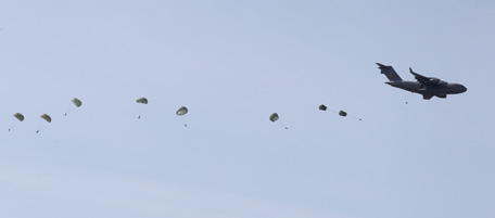 U.S. troops parachute out of a C-17 plane flying over Maniago, near the NATO airbase of Aviano, Italy, during an exercise, Tuesday, March 22, 2011. An American fighter jet crashed over North African country, both crew ejecting safely. The U.S. Africa Command said both crewmembers were safe after what was believed to be a mechanical failure of the Air Force F-15. The aircraft, based out of Royal Air Force Lakenheath, England, was flying out of Italy's Aviano Air Base in support of Operation Odyssey Dawn. (AP Photo/Luca Bruno)