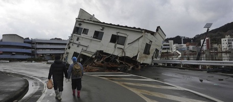 Local residents pass collapsed houses that were pushed onto a road in the city of Kesennuma in Miyagi prefecture on March 16, 2011. The official toll of the dead and missing following a devastating earthquake and tsunami that flattened Japan's northeast coast has topped 11,000, with 3,676 confirmed dead, police said. The total number of people unaccounted for in the wake of Friday's twin disasters rose by more than 800 to 7,558, the national police agency said in its latest update. AFP PHOTO / KIM JAE-HWAN (Photo credit should read KIM JAE-HWAN/AFP/Getty Images)
