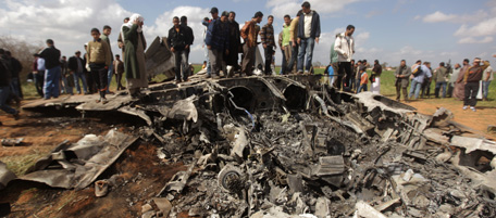 Libyans gather around the wreckage of a US F-15 fighter jet in Ghot Sultan, South-East of Benghazi on March 22, 2011 after crashing while on a mission against Moamer Kadhafi's air defences. The US Africa Command said the aircraft had experienced equipment malfunction over northeast Libya, adding that the two crew members had ejected and were safe. AFP PHOTO / PATRICK BAZ (Photo credit should read PATRICK BAZ/AFP/Getty Images)