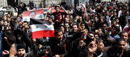 Syrian protesters chant slogans in support of President Bashar al-Assad as they hold up his picture and the national flag during a demonstration in the Old City of Damascus on March 25, 2011. AFP PHOTO/ LOUAI BESHARA (Photo credit should read LOUAI BESHARA/AFP/Getty Images)