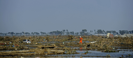 A Japanese rescuer walks across an area devastated by the tsunami in Sendai on March 13, 2011. The massive earthquake and tsunami on March 11 left more than 1,000 dead with at least 10,000 unaccounted for as shortages for food and fuel in many parts of eastern Japan creating havoc. AFP PHOTO / Philippe Lopez (Photo credit should read PHILIPPE LOPEZ/AFP/Getty Images)