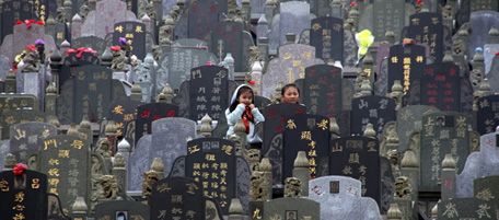 Two children walk amongst tombstones on the eve of Qing Ming, or Tomb Sweeping Day, in Jinjiang city in southeast China's Fujian province Monday, April 4, 2011. (AP Photo) CHINA OUT