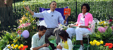 US President Barack Obama (L) prepares to read "Green Eggs and Ham" with First Lady Michelle Obama (R), Malia (seated-L) and Sasha on the South Lawn of the White House during the Annual Easter Egg Roll on April 5, 2010 in Washington, DC. The first White House Easter Egg Roll took place in 1878, when president Rutherford Hayes invited local children to roll eggs on the South Lawn.The egg roll has been held at the White House every year apart from the dark days of World War I and World War II. AFP PHOTO / Tim Sloan (Photo credit should read TIM SLOAN/AFP/Getty Images)