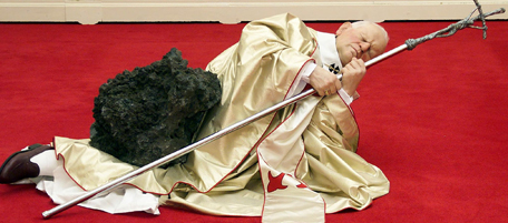 LONDON, UNITED KINGDOM - SEPTEMBER 22: A work of art in the "Apocalypse" exhibition by Italian Maurizio Cattelan of the Pope John Paul II lying on his side clutching a large cruclfix, apparently felled by a meteorite at the Royal Academy in London 22 September 2000. (AFP Photo/Hugo PHILPOTT) (Photo credit should read HUGO PHILPOTT/AFP/Getty Images)