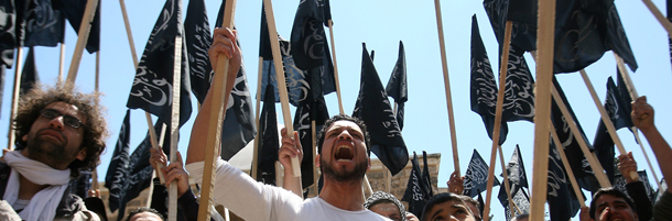 Supporters of pan-Islamic group Hizb al-Tahrir (Party of Liberation) wave the party's flags as they shout slogans during a protest against the Syrian regime in the northern Lebanese city of Tripoli on April 22, 2011. AFP PHOTO/STR (Photo credit should read -/AFP/Getty Images)