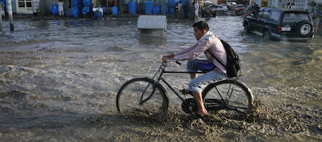 An Afghan youth rides his bicycle in a floodwater after a rain in Kabul, Afghanistan on Thursday, May 5, 2011. (AP Photo/Musadeq Sadeq)