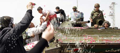 EDITOR'S NOTE: THIS PICTURE WAS TAKEN ON A GUIDED GOVERNMENT TOUR
Syrian women shower army troops with rose petals and rice as they pull out of the southern protest hub of Daraa on May 5, 2011 after a military lockdown of more than a week during which dozens of people were killed in what activists termed as "indiscriminate" shelling of the town, some 100 kms south of the capital Damascus. The Syrian military's political department chief insisted that troops "did not confront the protesters" in Daraa, adding that 25 soldiers were killed and 177 wounded during the military campaign to "search for terrorists". AFP PHOTO/LOUAI BESHARA (Photo credit should read LOUAI BESHARA/AFP/Getty Images)