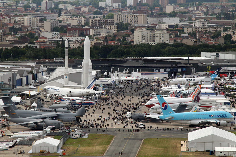 Vista aerea complessiva del parcheggio dei velivoli durante il salone di Le Bourget. A destra in primo piano l'Airbus A380 di Korean Air "prestato" per sostituire il modello dimostrativo di Airbus danneggiato all'apertura dello show. Subito dopo, il muso del più piccolo A400M, velivolo da trasporto militare del gruppo Eads (la casa madre di Airbus). Più avanti nella fila, il nuovo Boeing 747-8 e, in findo alla fila, un aereo "zero-G" attrezzato per sperimentare l'effetto dell'assenza di gravità. Nella fila di sinistra, invece, sono presenti oltre ad alcuni velivoli militari e civili (tra cui un C-5M Super Galaxy della Lockheed Martin e un Boeing 747-400 con la livrea di Air France) anche due vettori per i lanci orbitali.

(PIERRE VERDY/AFP/Getty Images)