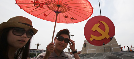 A Chinese woman holds up an umbrella near a giant communist party symbol set up ahead of the 90th anniversary of the founding of the Communist Party of China on July 1, on Tiananmen Square in Beijing, China, Monday, June 27, 2011. (AP Photo)