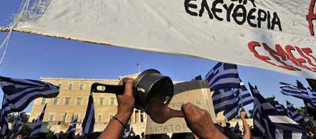 Greek 'Indignant' hold a banner reading '''bread-educastion-freedom'' during a protest in front of the Greek parliament for the fourth continous week against the new austeity package on June 19, 2011. Greek Prime Minister George Papandreou on Sunday urged political parties to forge a "national accord" and back him in a confidence vote in order to overcome the economic crisis amid social unrest. AFP PHOTO / LOUISA GOULIAMAKI (Photo credit should read LOUISA GOULIAMAKI/AFP/Getty Images)