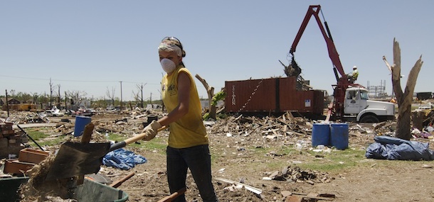 JOPLIN TORNADO - Cleanup from the F-5 tornado that destroyed much of Joplin, Mo, on Sunday, May 22, 2011, comes in small and large ways on Wednesday, June 15. Lindsay Castellaw, 16, Union City, Tenn, shovels debris from a home on South Wall while a larger debris collector works in the background. Castellaw was one of several members of the National Relief Network that were in Joplin assiting the massive cleanup effort.(AP/Mike Gullett)