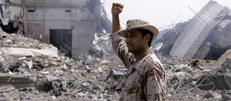 THIS PICTURE WAS TAKEN ON A GUIDED GOVERNMENT TOURTRIPOLI - JUNE 7: A Libyan soldier gestures as he stands in front of destroyed buildings at the Bab Al-Aziziya district where veteran leader Moamer Kadhafi has his base, in Tripoli on June 7, 2011 as NATO warplanes pounded the capital. (Photo by IMED LAMLOUM/AFP/Getty Images)