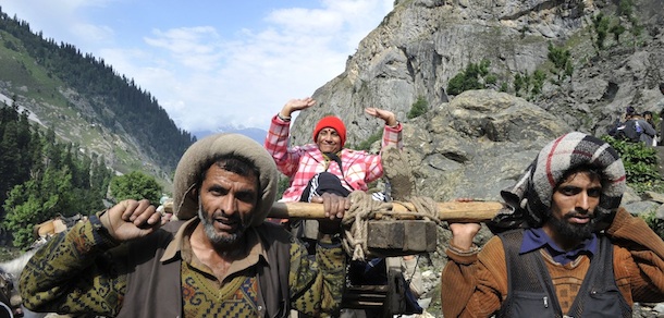 Hindu pilgrims are transported by Muslim porters from Pishu Top some 127 kms southeast of Srinagar, during the annual Hindu pilgrimage to the holy cave shrine of Amarnath on June 29, 2011. A three-tier security arrangement with the deployment has been put in place for the pilgrimage. Every year, hundreds of thousands of pilgrims trek through treacherous mountains in revolt-torn Kashmir, along icy streams, glacier-fed lakes and frozen passes, to reach the Amarnath cave, located at an altitude of 3880 m (12,729 feet), where a Shiva Lingam, an ice stalagmite shaped as a fallus and symbolising the Hindu God Shiva, stands for worship. AFP PHOTO/Tauseef MUSTAFA (Photo credit should read TAUSEEF MUSTAFA/AFP/Getty Images)