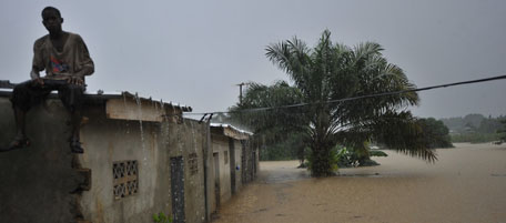 A man sits on a building roof corner as flood waters rush by in Abidjan's PK 18 district on June 30, 2011. According to authorities 160 sites in the Abijan district alone have been defined as risk areas due to torrential rains. AFP PHOTO / ISSOUF SANOGO (Photo credit should read ISSOUF SANOGO/AFP/Getty Images)