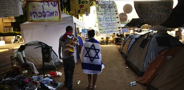 Israeli demonstrators walk at a tent camp in the centre of Tel Aviv on July 21, 2011 to protest against the rising prices of real estate in Israel. AFP PHOTO/MENAHEM KAHANA (Photo credit should read MENAHEM KAHANA/AFP/Getty Images)