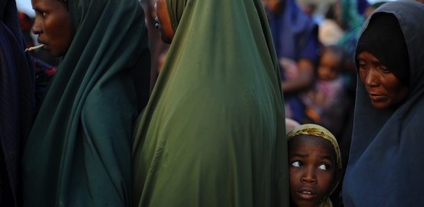 A young Somali girl who fled violence and drought in Somalia stands in line among adults outside a food distribution point in Dadaab refugee camp in northeastern Kenya on July 5, 2011. Dadaab, a complex of three settlements, is the world's largest refugee camp. Built to house 90,000 people and home to more than four times that number, it was already well over its maximum capacity before an influx of 30,000 refugees in the month of June. Upon arrival, the refugees find themselves tackling a chaotic system that sees new arrivals go days, even weeks, without food aid. "It still takes too much time for refugees to get proper assistance," Antoine Froidevaux, MSF's field coordinator in Dadaab told AFP. "The answer in terms of humanitarian aid is not satisfactory at all at the moment." 
 AFP PHOTO/Roberto SCHMIDT (Photo credit should read ROBERTO SCHMIDT/AFP/Getty Images)