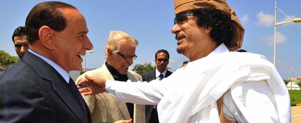 Libyan leader Moamer Kadhafi greets Italian Prime Minister Silvio Berlusconi (L) upon his arrival in the Mediterranean city of Benghazi, east of Tripoli, on August 30, 2008. Berlusconi said today Rome will invest five billion dollars in Libya over the next 25 years under a deal to resolve colonial era disputes that have long tarnished ties between Rome and Tripoli. Libyan protocol chief Nuri al-Mismari is seen in the middle. AFP PHOTO/POOL/LIVIO ANTICOLI (Photo credit should read LIVIO ANTICOLI/AFP/Getty Images)
