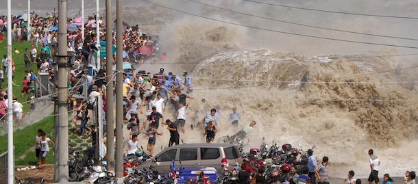 A crowd of Chinese tourists run away as a tidal bore breaks through the dam by the Qiangtang River in Haining, east China's Zhejiang province on August 31, 2011. Visitors gather to experience the Qianjiang Tidal Bore from early morning, an annual tradition for the residents living nearby. CHINA OUT AFP PHOTO (Photo credit should read STR/AFP/Getty Images)