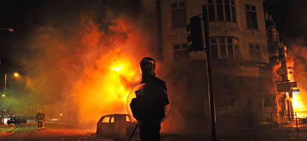 A british riot policeman stands guard in front of a burning building and burnt out car in Croydon, South London on August 8, 2011. Now in it's third night of unrest, London has seen sporadic outbreaks of looting and clashes both north and south of the river Thames. Numerous buildings were set on fire in Croydon including a 140 year old furniture store as hundreds of looters plundered high street shops of their goods. AFP PHOTO/Carl de Souza (Photo credit should read CARL DE SOUZA/AFP/Getty Images)