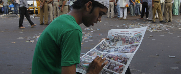 A supporter of anti-corruption activist Anna Hazare reads a newspaper while waiting outside Tihar prison cells, where Hazare is presently lodged, in New Delhi, India, Thursday, Aug. 18, 2011. Hazare struck a deal with police early Thursday to hold a 15-day public hunger strike against graft, ending a bizarre standoff at a New Delhi prison in which the activist turned his brief detention into a sit-in protest. Anna Hazare's ordeal has hit a chord with Indians fed up with rampant corruption. (AP Photo/Saurabh Das)