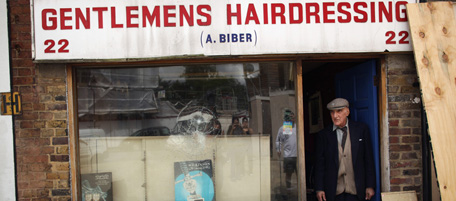 LONDON, ENGLAND - AUGUST 07: Aaron Biber, 89, stands outside his hairdressing salon that was ransacked during riots on Tottenham High Road on August 7, 2011 in London, England. Rioting broke out late last night in Tottenham and the surrounding area after the killing of Mark Duggan, 29 and a father-of-four, by armed police in an attempted arrest on August 4. (Photo by Dan Kitwood/Getty Images)