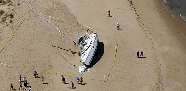 A vessel found beached on Sunday, Aug. 28, 2011, is lined with tape in Suffolk, Va. Two sailboat dwellers and their cat were rescued from the boat early Saturday in Ocean View in advance of Hurricane Irene. (AP Photo/The Virginian-Pilot, Amanda Lucier)