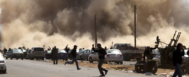 Libyan rebel fighters take cover as a bomb dropped by an airforce fighter jet explodes near a checkpoint on the outskirts of the oil town of Ras Lanuf on March 7, 2011. AFP PHOTO/MARCO LONGARI (Photo credit should read MARCO LONGARI/AFP/Getty Images)