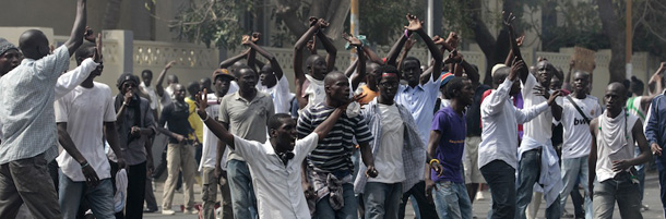 Men protesting proposed changes to the constitution gesture to police as they attempt to gather to demonstrate near the National Assembly, in central Dakar, Senegal Thursday, June 23, 2011. Police fired tear gas on thousands of protestors demonstrating Thursday morning against a proposed law that critics said could benefit Senegal's longtime leader President Abdoulaye Wade, and his family. (AP Photo/Rebecca Blackwell)